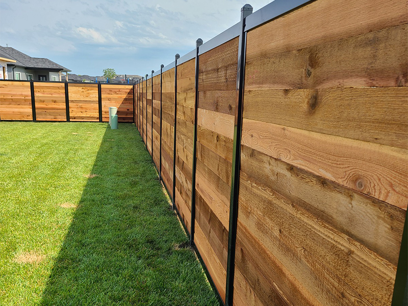 Photo of a fencetrak fence with black metal posts and horizontal wood panels
